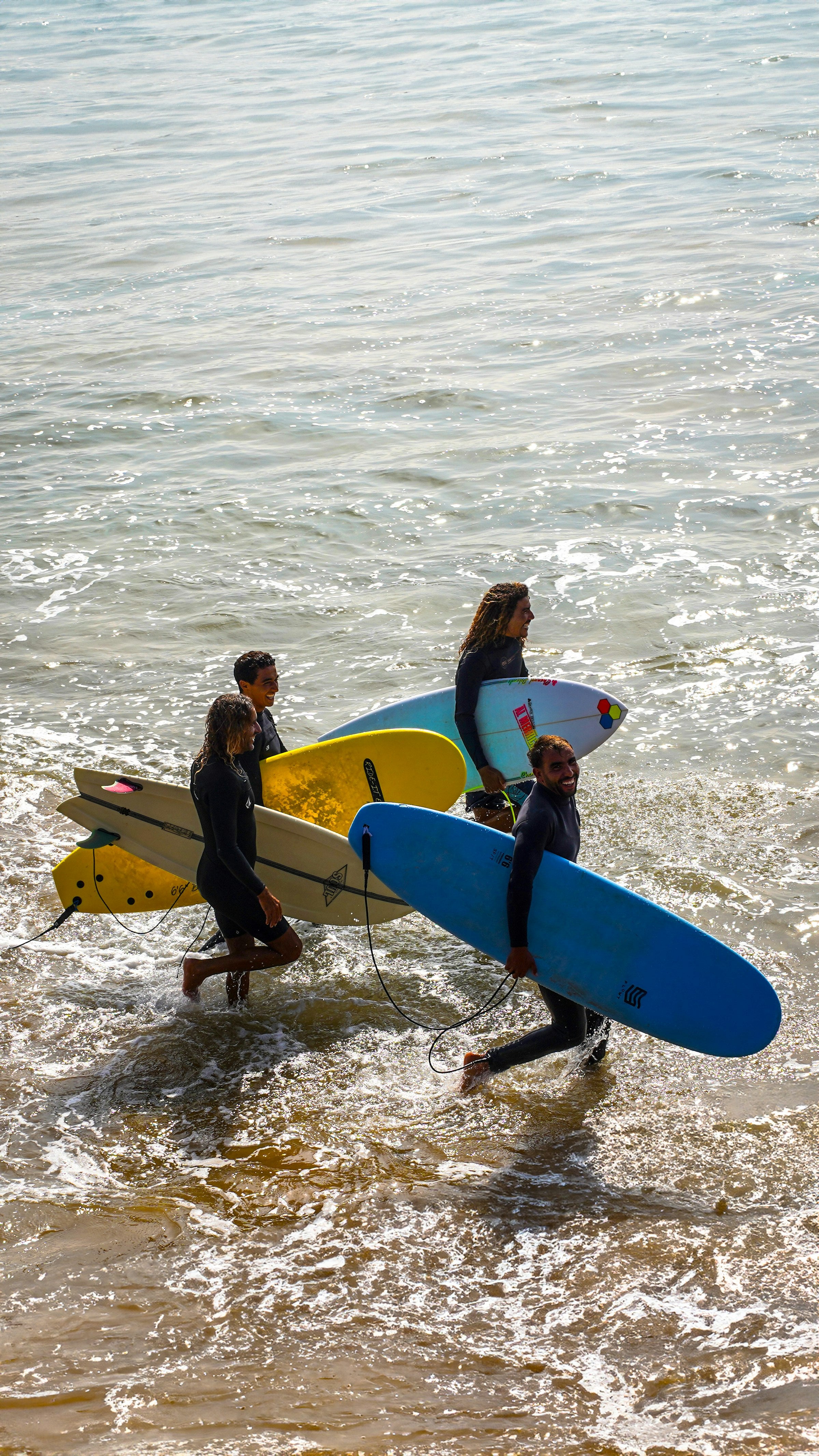 Group of surfers carrying surfboards into the ocean